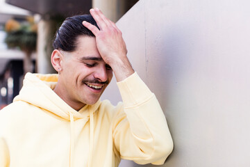young cool man laughing and slapping forehead like saying d’oh! I forgot or that was a stupid...