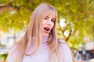young pretty woman looking happy and friendly, smiling and winking an eye at you with a positive...