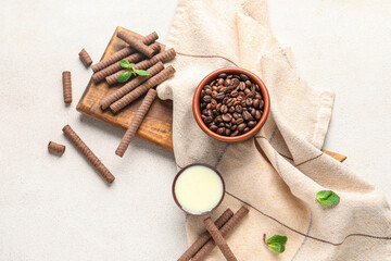 Board with delicious chocolate wafer rolls, coffee beans and condensed milk on white background