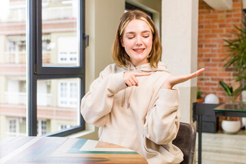 pretty caucasian woman smiling, feeling happy, carefree and satisfied, pointing to concept or idea on copy space on the side. home interior concept