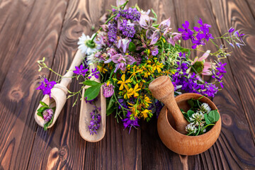 Summer medicinal herbs - St. John's wort, chamomile, clover near wooden mortar. Preparation of...