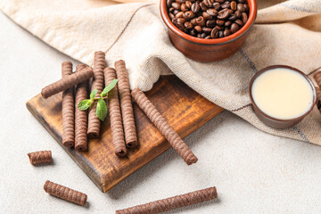Fototapeta na wymiar Board with delicious chocolate wafer rolls, coffee beans and condensed milk on white background