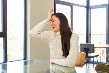 pretty caucasian woman laughing and slapping forehead like saying d’oh! I forgot or that was a...