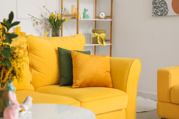 Interior of living room with yellow sofa, tulips and Easter eggs
