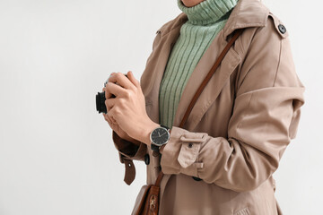 Woman with wristwatch and photo camera on light background, closeup