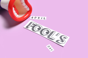 Toy megaphone and text APRIL FOOL'S DAY on color background