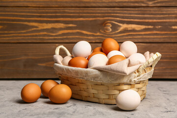 Wicker basket with Easter eggs on grey table near wooden wall