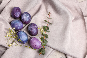 Painted Easter eggs, eucalyptus branch and gypsophila flowers on grey tablecloth