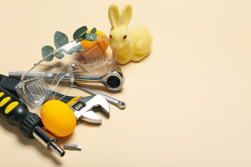 Work tools with Easter eggs and toy rabbit on beige background