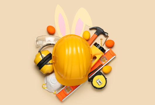 Builder's equipment with bunny ears and Easter eggs on beige background