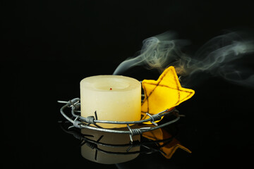 Candle with barbed wire and Jewish badge on dark background. International Holocaust Remembrance Day