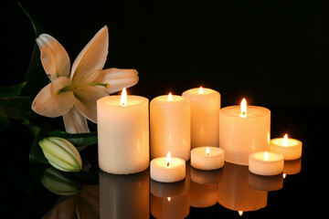 Burning candles with lilies on dark background. Mourning concept