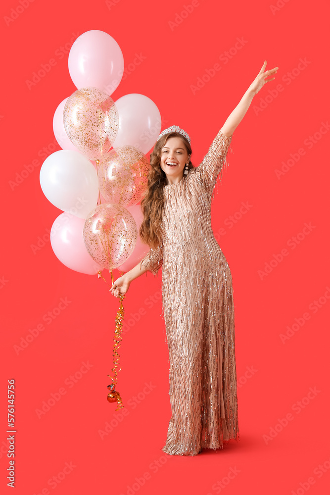 Poster happy young woman in shiny prom dress with balloons on red background