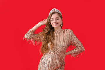 Young woman in tiara and shiny prom dress on red background © Pixel-Shot
