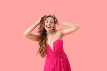 Young woman in crown and bright prom dress on pink background © Pixel-Shot