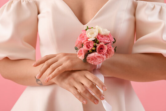 Young woman in prom dress with corsage on pink background, closeup