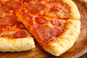 Slice of delicious pepperoni pizza on wooden board, closeup