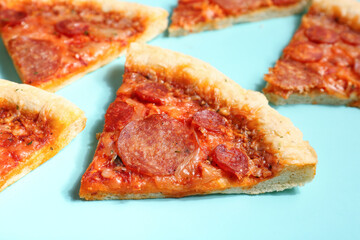 Slices of delicious pepperoni pizza on turquoise background, closeup