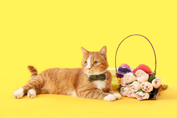 Fototapeta na wymiar Cute cat, basket with Easter eggs, gifts and tulips on yellow background
