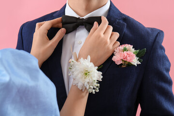 Young girl adjusting bowtie of her prom date on pink background, closeup © Pixel-Shot