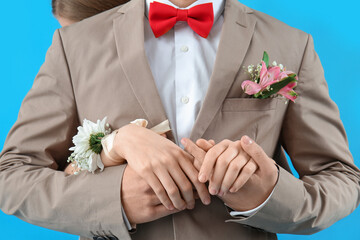 Young guy in suit and his prom date on blue background, closeup