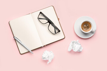 Composition with notebook, eyeglasses, crumpled paper balls and cup of coffee on pink background