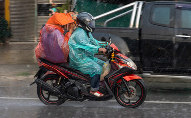 Fototapeta na wymiar Couple in raincoats drive in rain