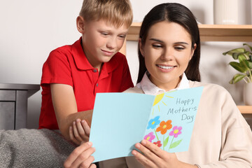 Obraz premium Happy woman receiving greeting card from her son at home