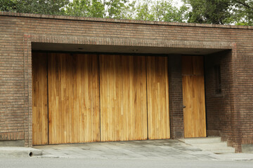 Fototapeta na wymiar Brick wall with wooden entrance door and gates. Exterior design