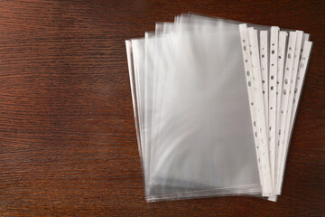 Punched pockets on wooden table, flat lay. Space for text