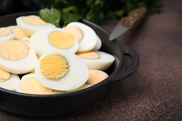 Fresh hard boiled eggs and parsley on brown table, closeup. Space for text