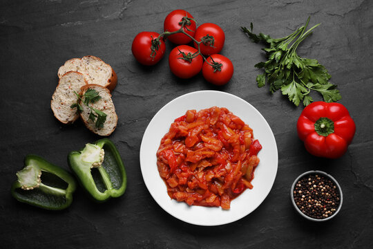 Delicious lecho and ingredients on black table, flat lay