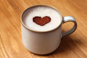 Mug of aromatic coffee with heart shaped decoration on wooden table