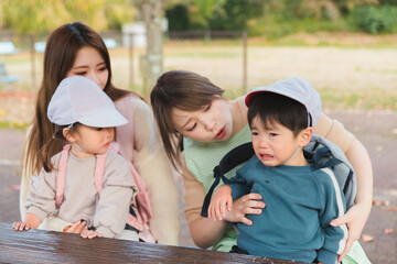 秋の公園で泣く園児と困る保育士（保育園・幼稚園・保母）
