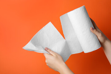Woman tearing paper towels on orange background, closeup