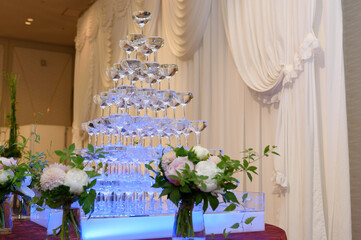 Blue champagne tower at a wedding. White curtains in a background.
