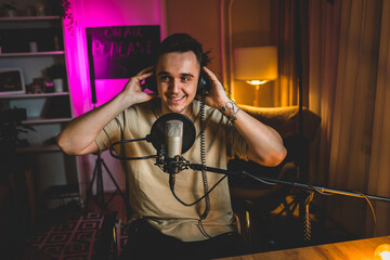 A portrait of one young man in his home podcast studio at night 