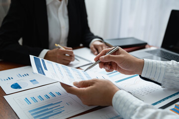 Two Asian businessmen met in the office and pointed to analysis charts and graphs of business growth and financial performance.