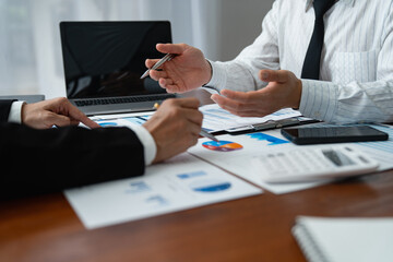 Two Asian businessmen met in the office and pointed to analysis charts and graphs of business growth and financial performance.