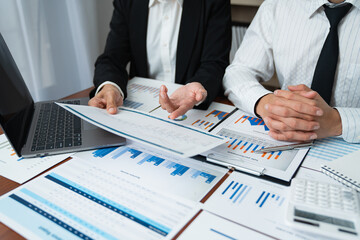Two Asian businessmen met in the office and pointed to analysis charts and graphs of business growth and financial performance.