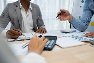 A group of Asian businessmen is brainstorming and discussing figures in company financial papers. Financial analyst pointing to data graph to check company with meeting concept.