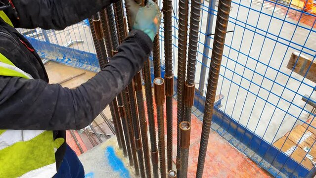 Steel fixer screwing threaded bar in coupler.