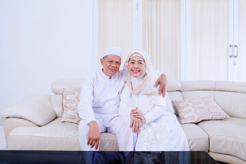 Elderly Asian muslim couple sitting on sofa