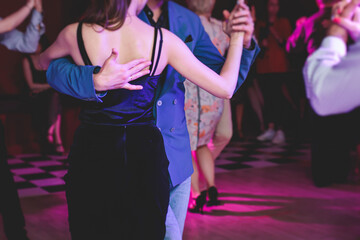 Couples dancing traditional latin argentinian dance milonga in the ballroom, tango salsa bachata kizomba lesson in the red and purple lights, festival, lesson class in dance school class academy - obrazy, fototapety, plakaty
