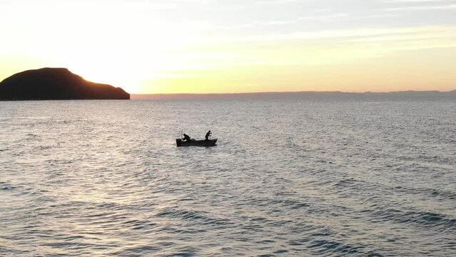Aerial of Silhouette of fishermen in small fishing boat Sea of Cortez in Baja at sunset