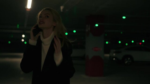 Angry annoyed stressful businesswoman walking on dark car parking alone Caucasian blonde woman female girl client arguing speak mobile phone shouting swear on taxi service expressing negative emotion