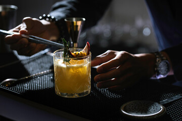 Fototapeta na wymiar Bartenders making the cocktail glass on the bar counter in the dark background.