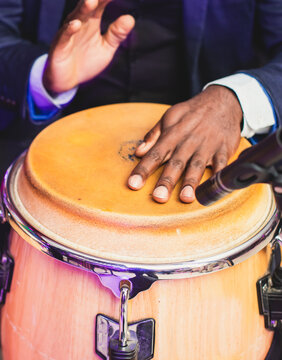 Bongo drummer percussionist performing on a stage with conga drums set kit during jazz rock show performance, tumbadora quinto with latin cuban afro-cuban jazz band performing in the background