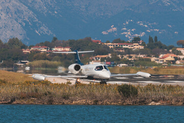 Fototapeta na wymiar View of modern private reactive aircraft on an runway airfield ready to take off, airstrip with business jet airplane before the flight with mountains in the background in a summer sunny day