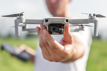 The drone pilot holds the quadcopter in front of him, in the other hand the control panel.